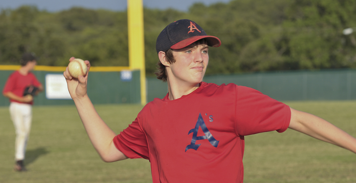 Teenage boy throwing a pitch at a baseball game. 