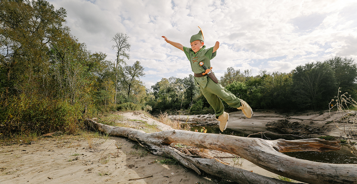 Miles as Peter Pan jumping off tree trunk 