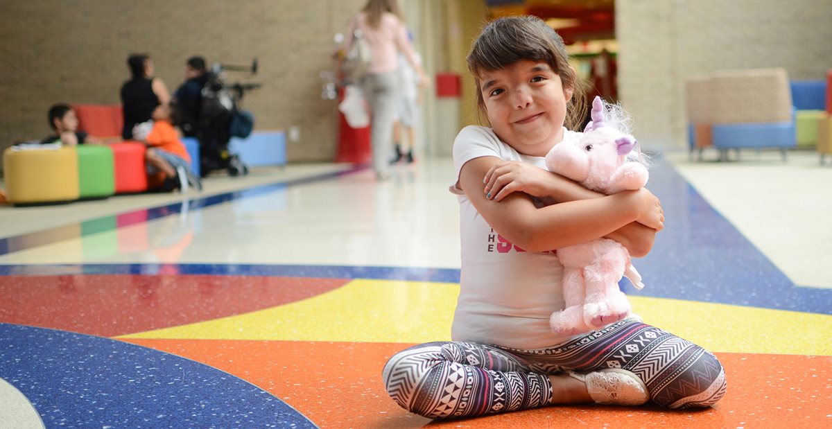 Child with magnetic spinal rods holds toy at Texas Scottish Rite Hospital for Children 