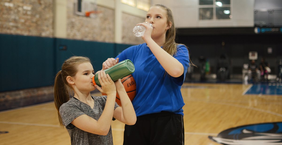 Young athletes drinking water on a basketball court